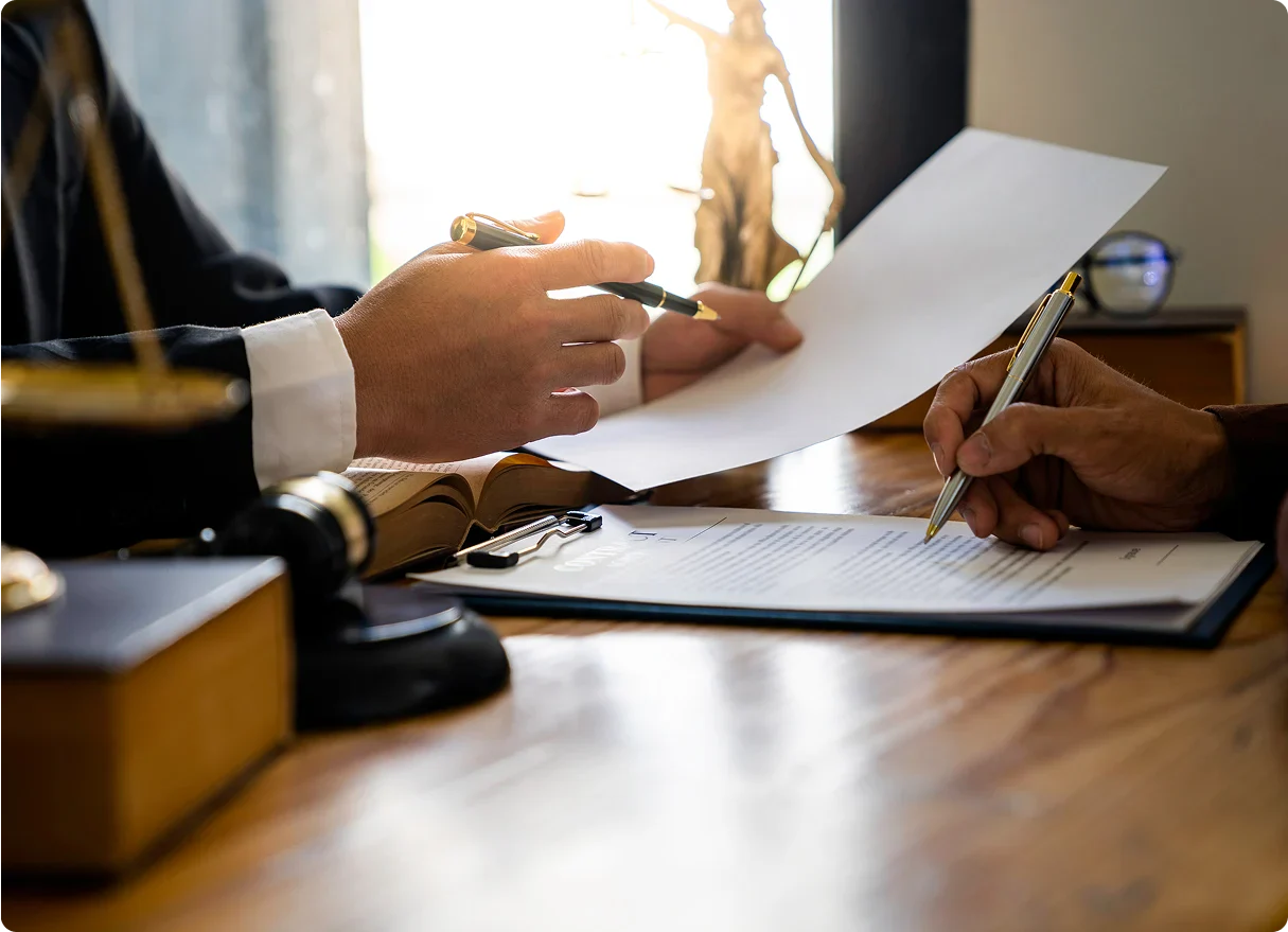 A lawyer discusses a document with a client, with legal books and a gavel visible on the desk, symbolizing legal counsel and agreements.